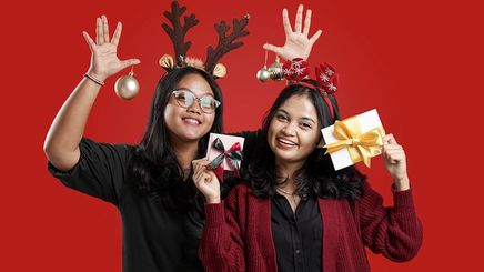 Two women wearing Christmas ornaments