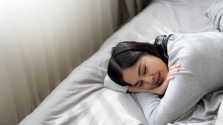 Asian woman in gray sleeping in bed