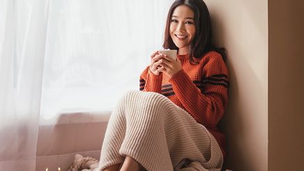 Asian woman wearing a sweater by the window