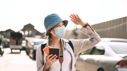 Asian woman with hat and face mask shielding face from sun