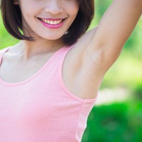 Smiling woman in pink tank top showing one of her underarms.