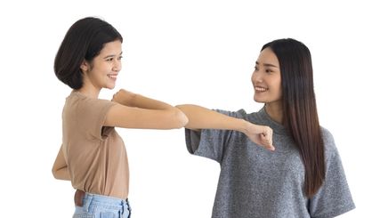 Two Asian girls bump elbows 
