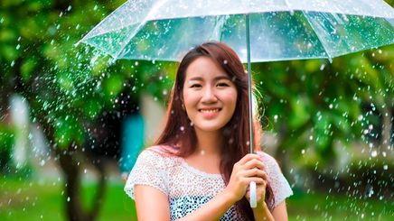 Asian woman carrying a transparent umbrella in the rain.