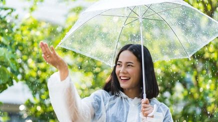 Smiling woman holding an umbrella while raining. 