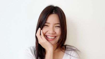 a woman with braces touching her face