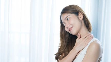 Asian woman with long hair touching her neck