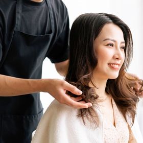 Asian woman happily getting her hair styled at a salon.