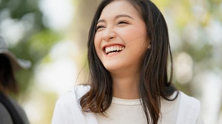 Closeup of a happy Asian woman in a white top.