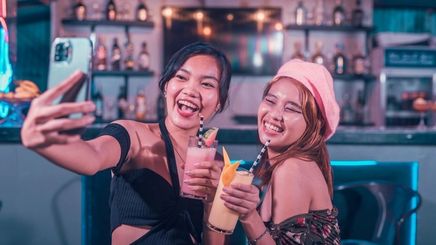 Female Asian friends drinking shakes at a bar.