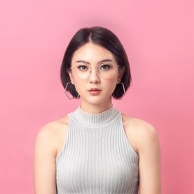 Asian woman with glasses and short bob haircut in front of pink background