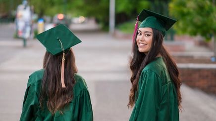 Two female graduates wearing green togas. 