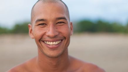 Asian man in his 30s smiling at the beach