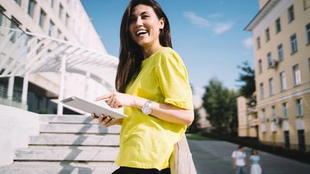 Asian woman with long hair wearing a lime green shirt, smiling under the sun.