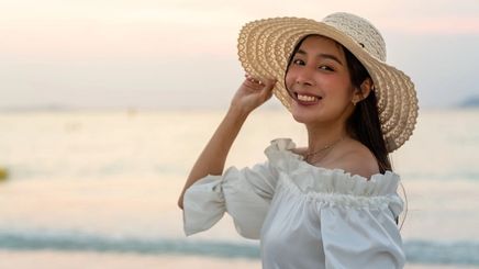 Asian woman wearing a straw hat by the water 