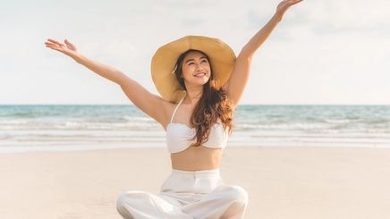 Happy Asian woman sitting on the sand.