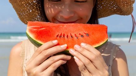 Asian woman eating watermelon at the beach 