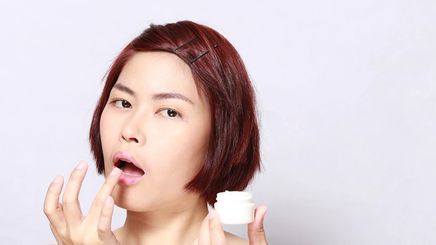Asian woman applying lip treatment
