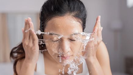 Asian woman splashing face with water