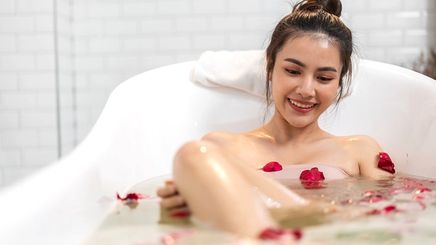 Asian woman in the tub with rose petals