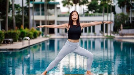 Asian woman in warrior pose by the pool