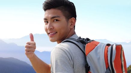 Asian man giving a thumbs up while on a hike