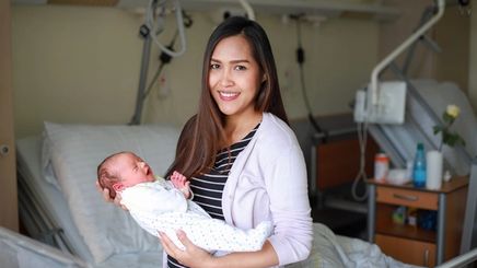 Asian mother holding newborn in hospital. 