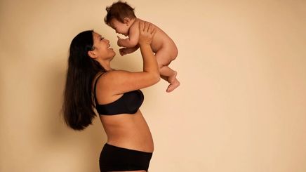 Asian mom in black underwear carrying a baby.