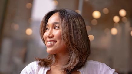 Filipino woman with glowing skin, smiling into the distance