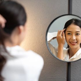Asian checking her hair on a mirror