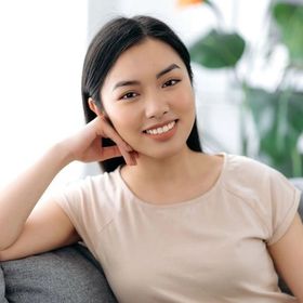 Asian woman leaning on a couch, smiling