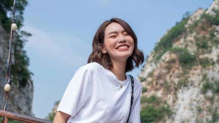 Happy Asian woman in a white T-shirt wearing minimalist makeup.