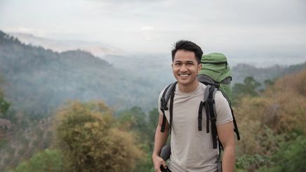 Filipino man smiling while hiking in the outdoors.