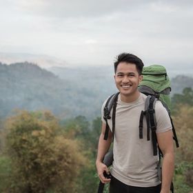 Filipino man smiling while hiking in the outdoors.