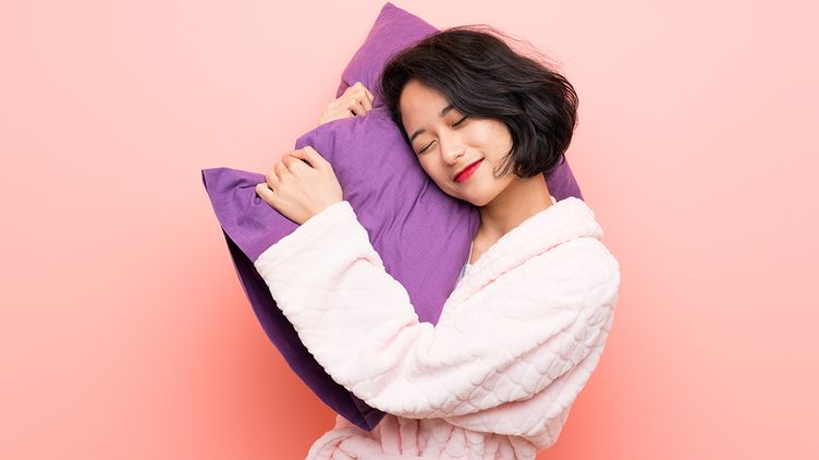 Asian woman in a robe holding a purple pillow