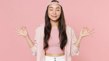 Smiling young woman holds her hands in yoga gesture 