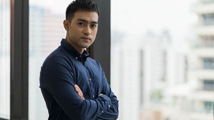 Man standing near a window while crossing his arms.