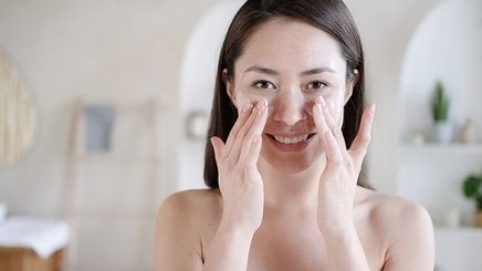 Asian girl applying product on cheeks