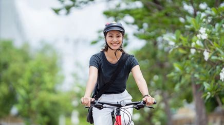 Asian woman rides bike outdoors 