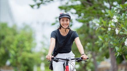 Asian woman rides bike outdoors 