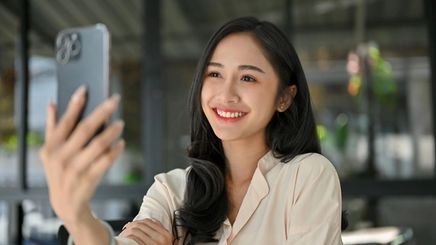 Woman taking a selfie with a smartphone while relaxing at a café.
