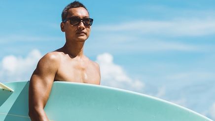 Asian man holding a surfboard