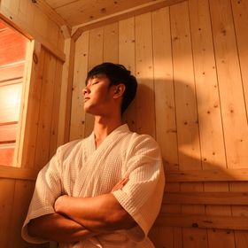 Man in bathrobe enjoying a steam bath in a wooden room.
