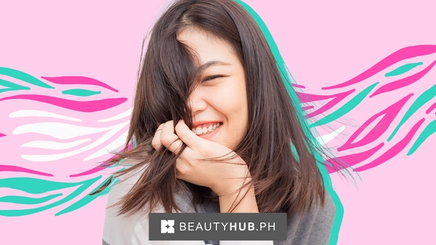 Asian woman smiling while holding hair on her face