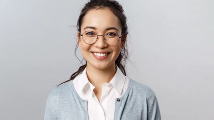 Asian woman wearing glasses and blazer with messy ponytail