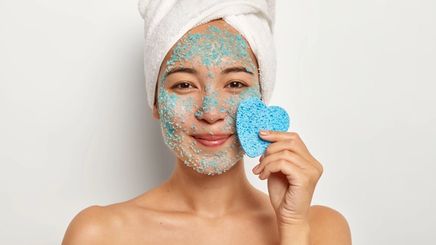 A woman applying a face mask.