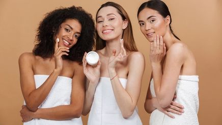 Diverse women applying moisturizer.