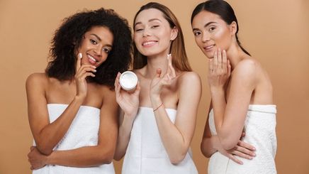 Diverse women applying moisturizer.