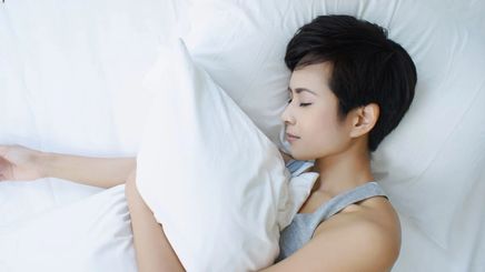 Asian woman with short hair sleeping on white pillows 