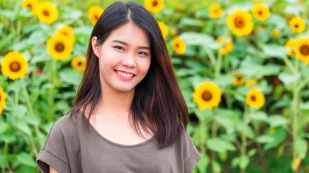 A portrait of smiling woman in a sunflower garden.