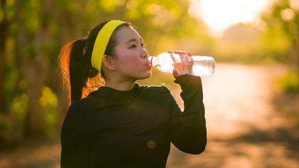 Athletic Asian woman drinking water